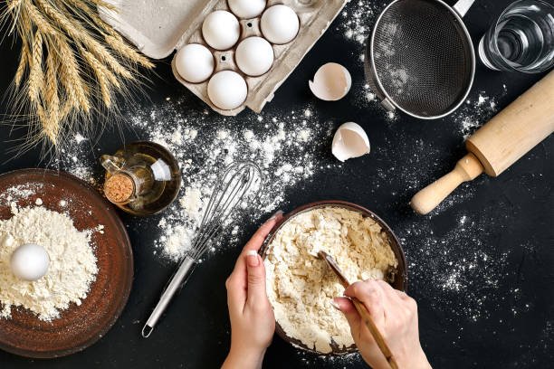 istock Female hands making/ mixing dough in brown bowl on black table, baking preparation close-up 917279756