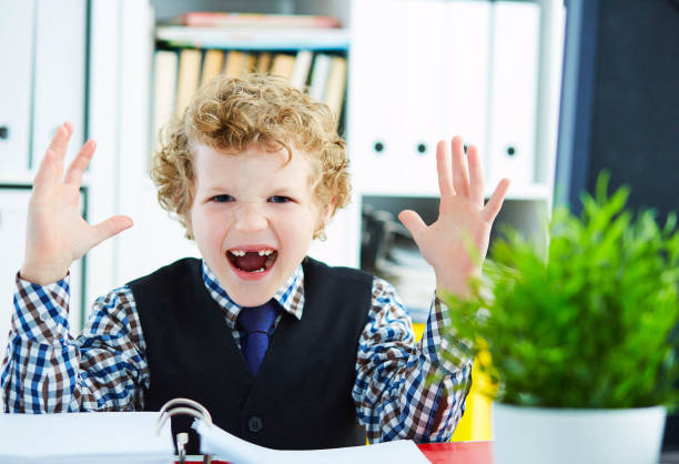 istock Little angry boy screams holding his hands over folder with file 917280584
