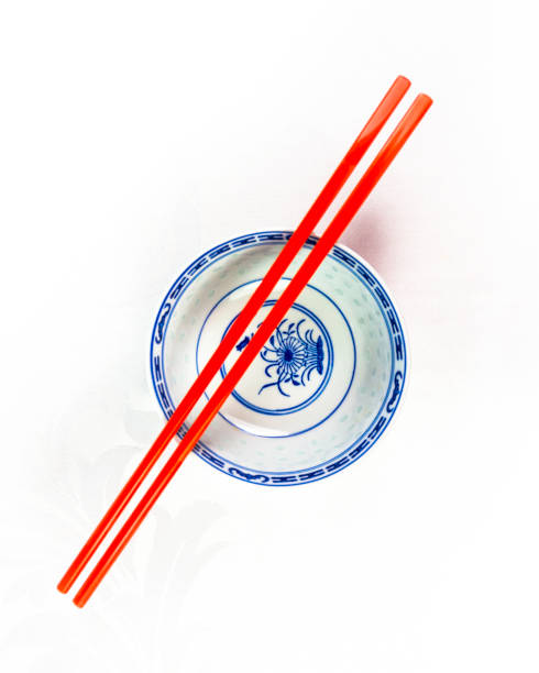 chise table setting of rice bowl spoon and chopsticks on red background