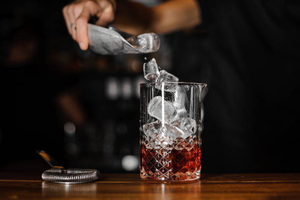 barman mette i cubetti di ghiaccio in un bicchiere - glass bar relaxation red foto e immagini stock