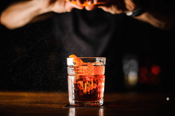 istock bartender with glass and orange peel preparing cocktail at bar 917284254