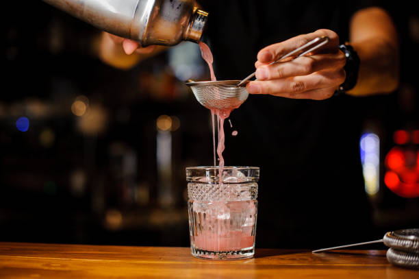 istock Bartender hand pouring pink cocktail drink in bar 917284396