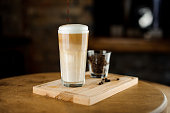 Hot latte coffee in a high glass cup on a wooden board