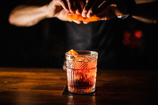 Bartender con cáscara de naranja y cocktail preparando cócteles en el bar photo