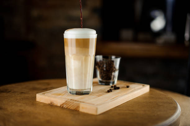 heißen latte, die in einem hohen glas-tasse auf einem holzbrett kaffee - biscotti coffee cappuccino latté stock-fotos und bilder