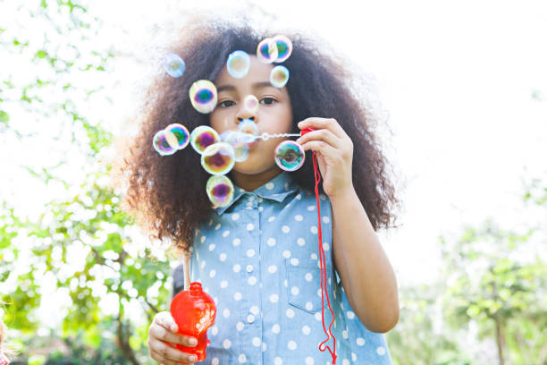 istock little girl blowing soap bubbles in park 917291728