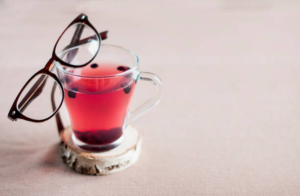 chá de mirtilo em um copo de vidro e com óculos em uma moldura marrom nele, espaço para texto. - zeaxanthin - fotografias e filmes do acervo