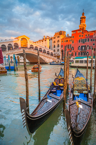 Classic panoramic view with traditional Gondolas on famous Canal Grande with famous Rialto Bridge in the background in beautiful golden evening light at sunset in summer, Venice, Italy