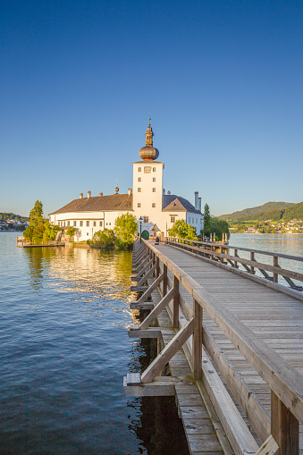 Beautiful view of famous Schloss Ort with wooden bridge at Lake Traunsee in beautiful golden evening light at sunset, Gmunden, Salzkammergut region, Austria