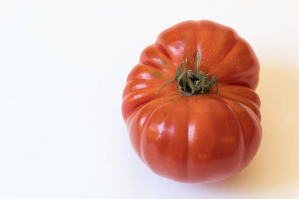 A large, red heirloom tomato arranged on a blue plate.