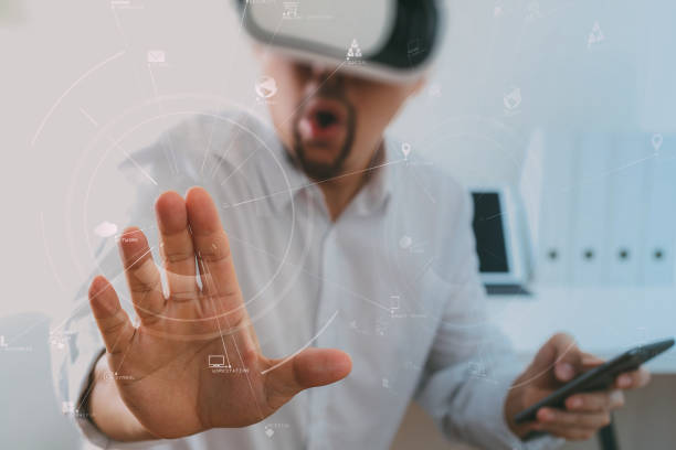istock businessman wearing virtual reality goggles in modern office with mobile phone using with VR headset 917306720
