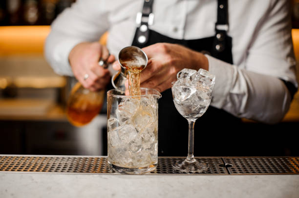 istock Bartender adding alcoholic drink into a glass filled with ice cubes 917325174