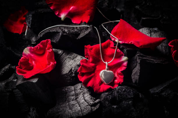 istock Silver heart  shape locket with necklace on black charcoal texture background 917332438