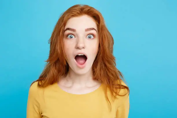 Close up Portrait young beautiful attractive redhair girl shocking with something. Blue Pastel Background. Copy space