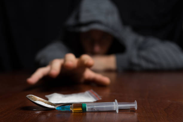 adicto a la mesa tira su mano a la jeringa con la dosis - narcotic drug abuse addict heroin fotografías e imágenes de stock