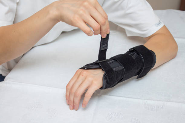The woman puts the wrist stabilizer on her arm.