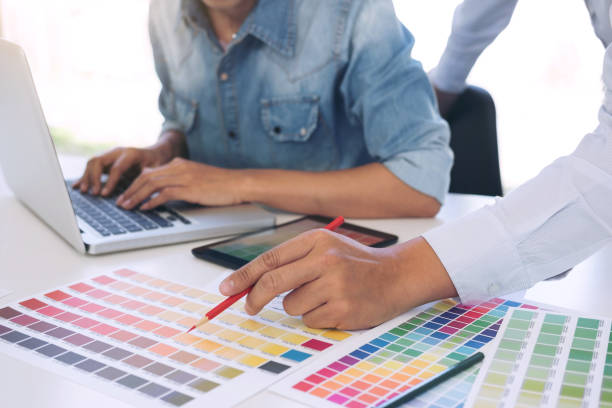 istock Two young interior design or graphic designer working on project of architecture drawing with work tools and color swatches, colour chart in digital tablet at workplace 917336552