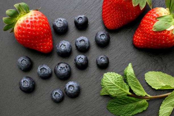 istock Strawberries, group of blueberries and some mint leaves on slate plate 917339640