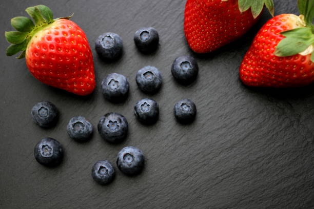 istock Strawberries with group of blueberries on slate plate 917340168