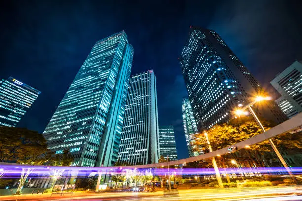 Asia Business concept for real estate and corporate construction - looking up night view in road intersection of shinjuku, the silhouettes of skyscrapers reflect twilight sky in Tokyo, Japan