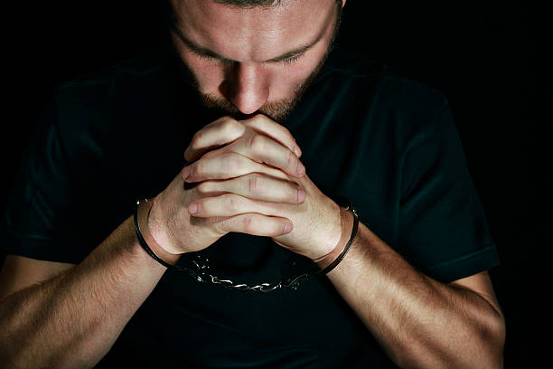 Man in handcuffs praying worriedly stock photo