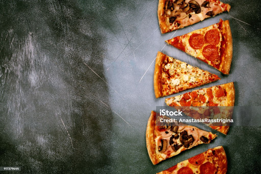 Slices of pizza with different fillings on a dark textured background Pizza Stock Photo