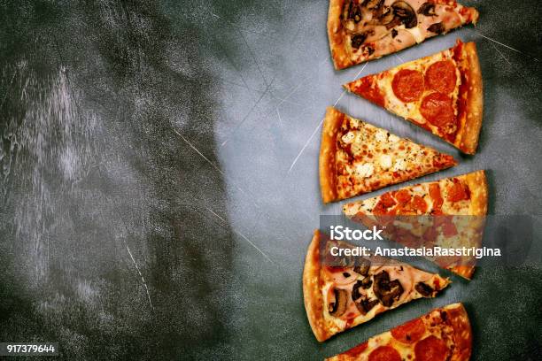 Slices Of Pizza With Different Fillings On A Dark Textured Background Stock Photo - Download Image Now