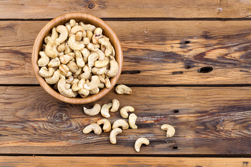 Raw cashews close-up in bowl on a wooden table. Top view