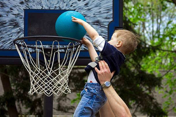 Slam dunk Adult helping boy score a basketball shot toddler hitting stock pictures, royalty-free photos & images