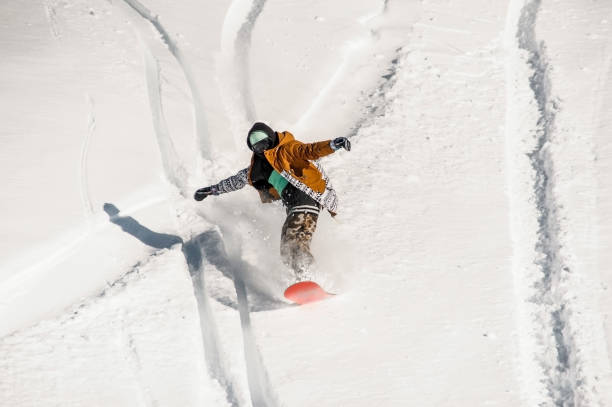 istock Snowboarder in sportswear riding down the mountain slope 917392678