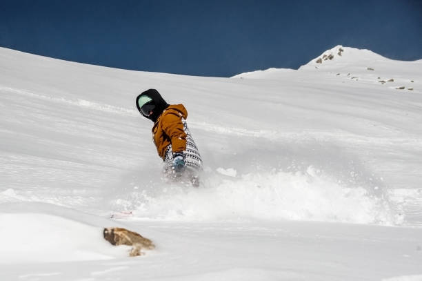 istock Snowboarder in sportswear riding down the mountain slope 917395890