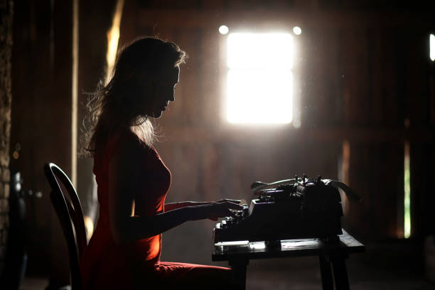 istock A girl in retro style prints on an old typewriter 917403814