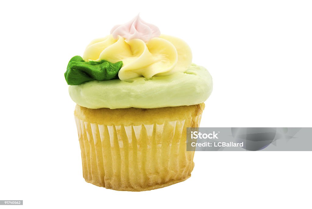 cupcake with green pink and yellow frosting isolated on white one yellow homemade cupcake in a paper cup holder. It has pastel colored buttercream icing in shades of green, pink, and yellow. This image is isolated on white. It was shot indoors under natural day light.  Baked Stock Photo