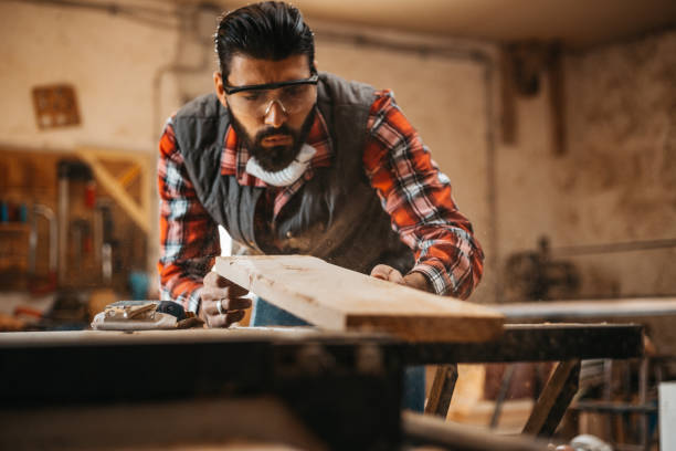 istock Carpenter blowing dust from wooden plank 917420496
