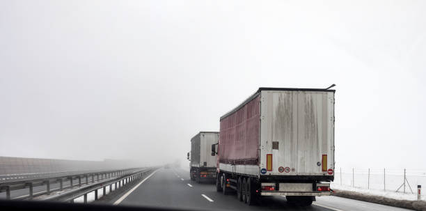 istock Two Semi-Trucks Driving on Highway Thru Fog 917421078