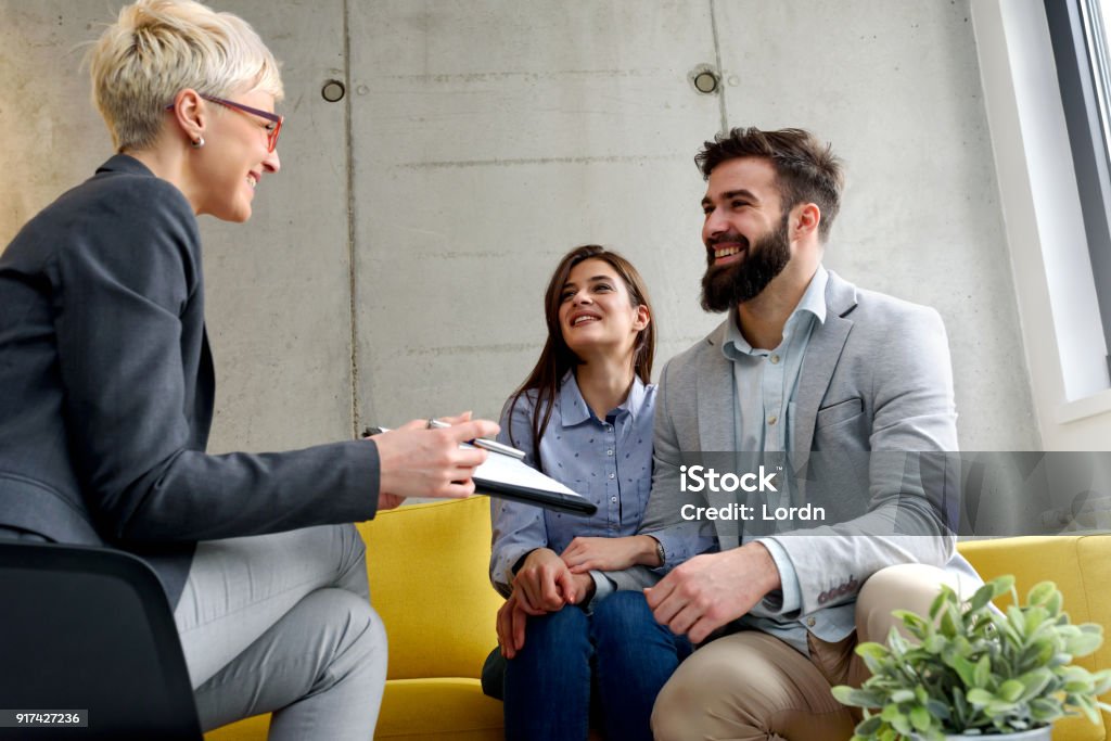 Young married couple at their counselor young married couple with real estate agent, financial advisor or marriage counselor Psychotherapy Stock Photo