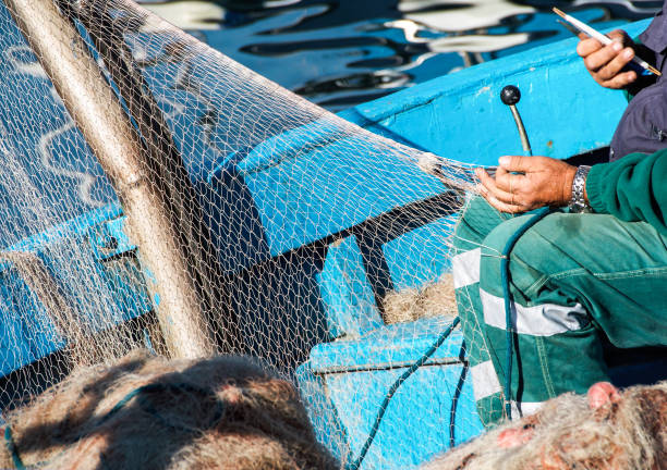 pescatore riparazione di una rete nella sua barca - beach rope nautical vessel harbor foto e immagini stock