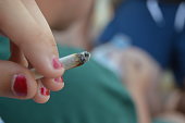 Joint in hand with young man in the background. Joint in hand with young man in background.