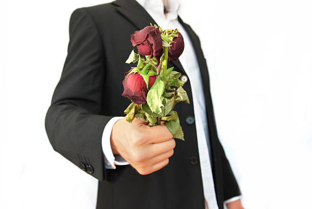 Portrait of a handsome young man wearing a suit and holding a bunch of roses