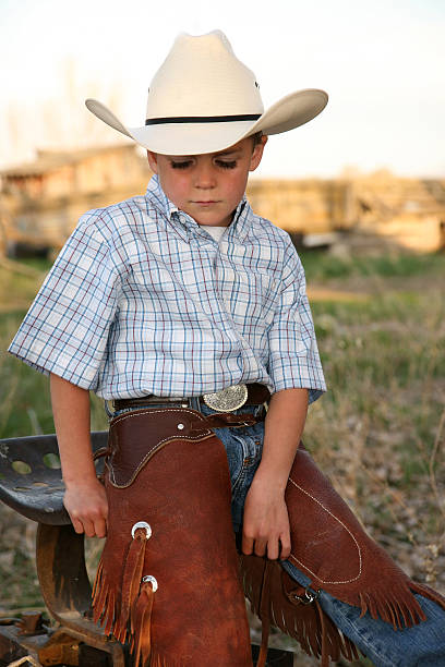 istock Young Cowboy sitting on a tractor looking down. 91744932