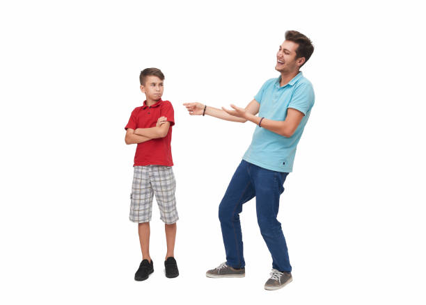 Young man making fun of little boy over a white background Young man making fun of his little brother over a white background. Horizontal composition. Studio shot. teasing photos stock pictures, royalty-free photos & images