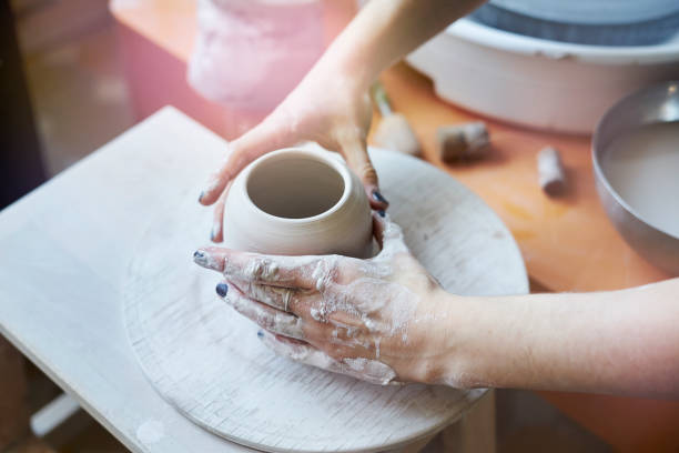 istock Ceramic studio, craft working process with clay potter's wheel, close-up of hands doing a pot or a vase, object 917450432