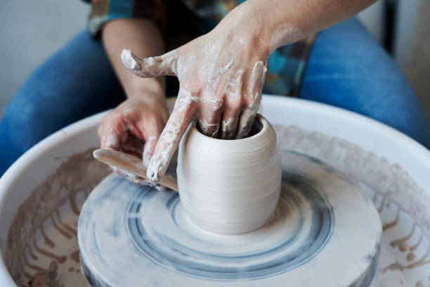 istock Close-up of hands doing a pot or a vase in ceramic studio, craft working process with clay potter's wheel 917450678