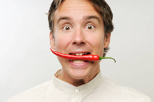 istock Man holding a long red chili in his mouth on white backing 91745075