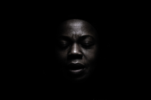 Black face in deep shadow , powerful expression.