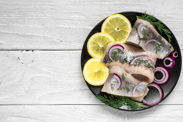 istock marinated herring fillet with pepper, herbs, onion and lemon on black plate on white background 917455008