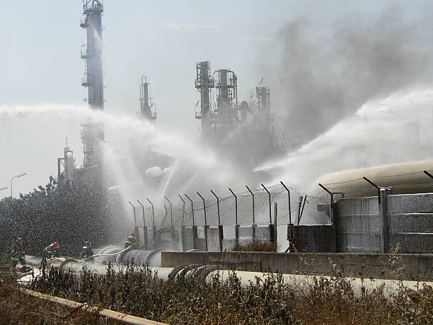 Firemen putting out a fire with hoses of water at refinery stock photo