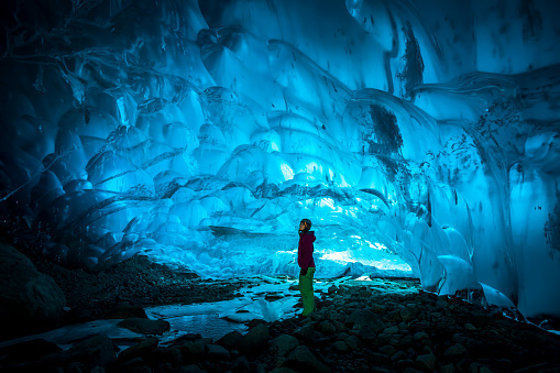 Woman exploring glacial ice cave.
