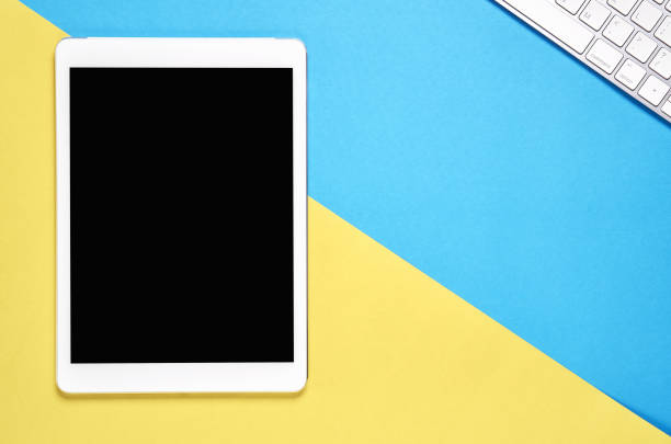 istock Top view, Modern workplace with tablet placed on a pastel yellow background. Copy space suitable for use in graphics. 917468076