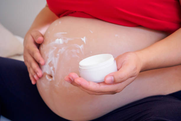 istock Pregnant Woman applying stretch marks cream on her belly 917471312